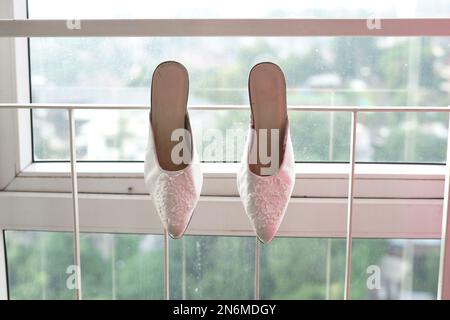 Ein Paar Hochzeitsschuhe für Braut und Groom, die am Zaun hängen Stockfoto