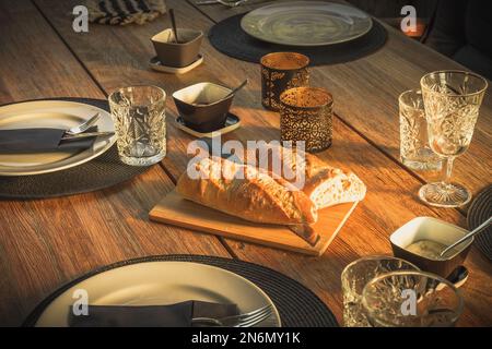 Liegender Gartentisch mit Baguette-Brot zum Abendessen in der Abendsonne Stockfoto