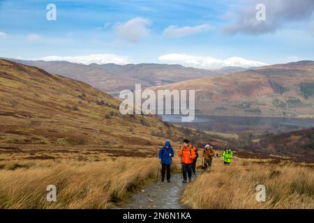 Wanderer auf dem Weg nach Ben Vorlich mit einem schneebedeckten Ben Lawers im Hintergrund. Stockfoto