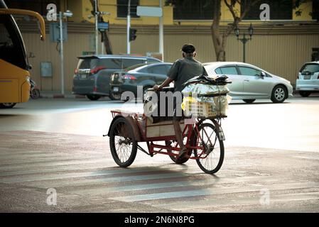 Bangkok, Thailand – 18. Januar 2013: Der alte Mann fährt auf seinem Dreirad. Ein typischer einkommensschwacher Mensch nutzt ein Dreirad, das als „Saleng“ bezeichnet wird, um seine Waren zu befördern. Stockfoto