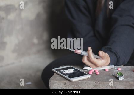 Junge Frau Hand hält eine Spritze und Drogenüberdosis, das Konzept von Verbrechen und Drogensucht. 26. Juni, Internationaler Tag gegen Drogenmissbrauch. Stockfoto