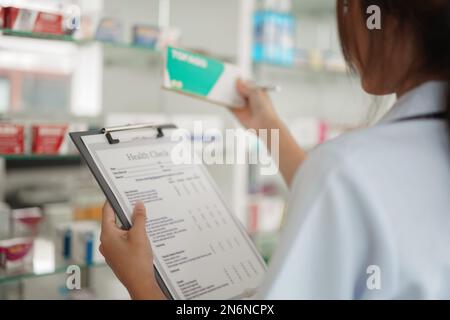 Medizin- und Gesundheitskonzept, Apothekerin halten Medikamentenkiste auf Checkliste in Papier in der Drogerie. Stockfoto