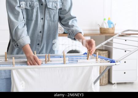 Eine Frau, die saubere Wäsche an einen Wäscheständer im Badezimmer hängt, eine Nahaufnahme Stockfoto