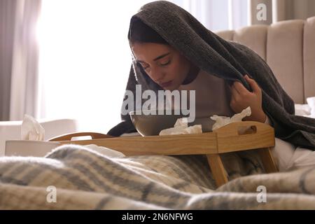 Eine Frau mit Karo, die über der Schüssel inhaliert Stockfoto