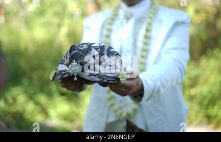 Bräutigam in Weiß, traditionelles Hochzeitskleid mit traditionellem Kopfkleid Stockfoto