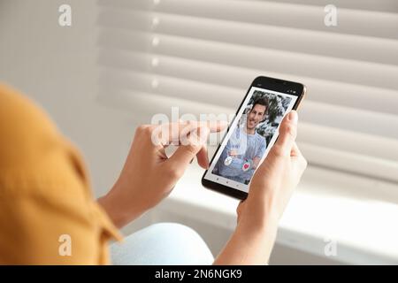 Frau besucht Dating-Seite über Smartphone drinnen, Nahaufnahme Stockfoto