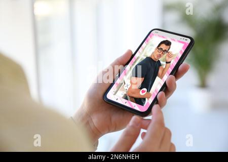 Frau besucht Dating-Seite über Smartphone drinnen, Nahaufnahme Stockfoto