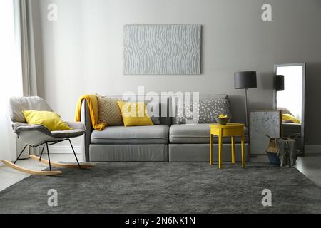 Stilvolles Wohnzimmer mit Sofa. Innendesign in Grau und Gelb Stockfoto