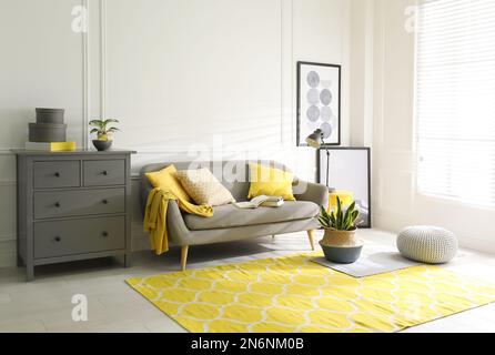 Stilvolles Wohnzimmer mit Sofa. Innendesign in Grau und Gelb Stockfoto