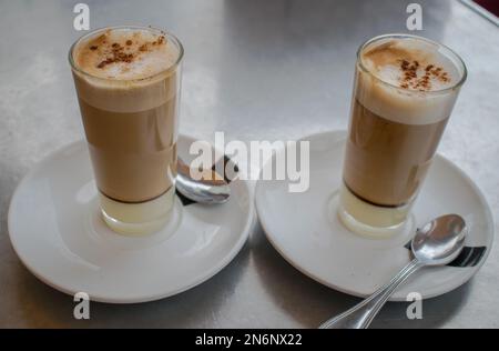Kaffee mit Milch in Glas Schale auf Metall Tisch Stockfoto