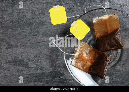 Untertasse mit gebrauchten Teebeuteln auf grauem Tisch, Draufsicht. Platz für Text Stockfoto