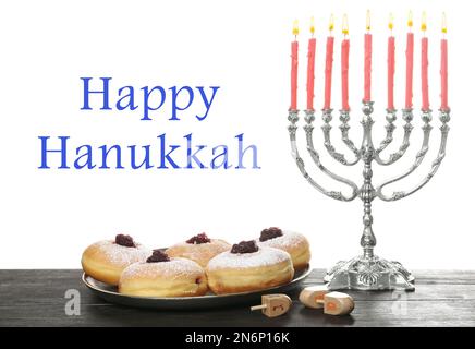 Frohes Chanukka. Silbermenorah, Sufganiyot und Dreidel auf Holztisch Stockfoto