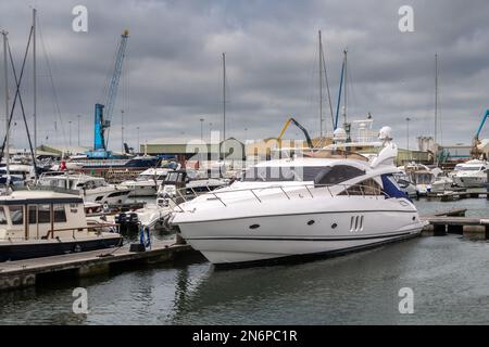 Ein weißer Sunseeker Manhattan 66 namens Silver Spirit, der im Yachthafen am Poole Quay vor Anker liegt. Der Yachtschirm ist bedeckt mit anderen Booten und Industrie-U Stockfoto