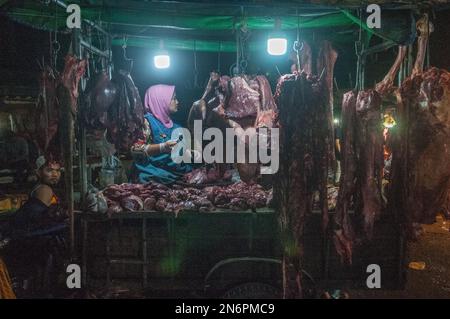 Eine muslimische Frau, die rohes Fleisch auf dem Hauptmarkt für Gemüse und Fleisch, Phsar Dumkor, bei Nacht in Phnom Penh, Kambodscha, verkauft. © Kraig Stockfoto