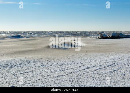 Nahaufnahme des eisigen Meeres, gefrorene Wellen, Felsen und Sonnenblendung auf dem Eis Stockfoto