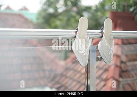 Ein Paar Brautschuhe, die für die Hochzeitszeremonie am Balkonzaun hängen Stockfoto