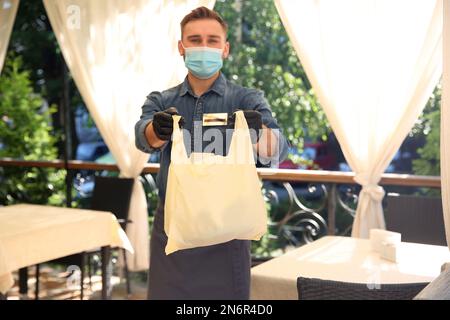 Kellner mit gepackten Speisen zum Mitnehmen im Restaurant. Gastronomie während der Coronavirus-Quarantäne Stockfoto