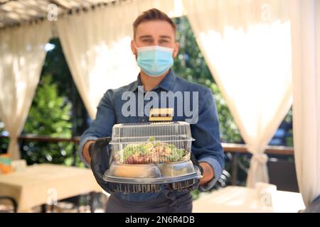 Kellner mit gepackten Speisen zum Mitnehmen im Restaurant. Gastronomie während der Coronavirus-Quarantäne Stockfoto