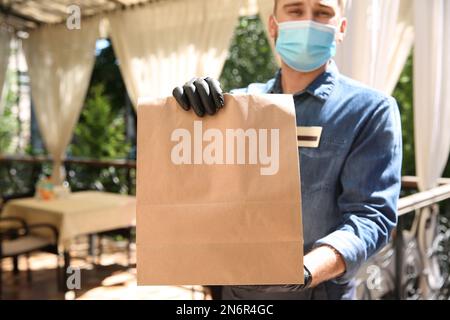 Kellner mit gepackten Speisen zum Mitnehmen im Restaurant. Gastronomie während der Coronavirus-Quarantäne Stockfoto