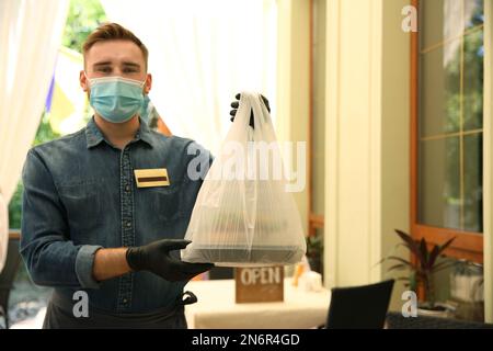 Kellner mit gepackten Speisen zum Mitnehmen im Restaurant. Gastronomie während der Coronavirus-Quarantäne Stockfoto