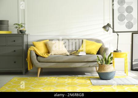 Stilvolles Wohnzimmer mit Sofa. Innendesign in Grau und Gelb Stockfoto