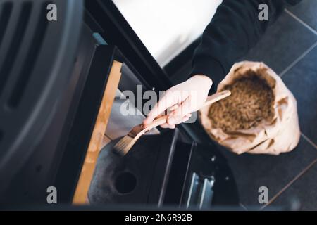 Mann, der Pelletofen mit Bürste reinigt Stockfoto