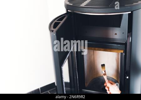 Mann, der Pelletofen mit Bürste reinigt Stockfoto