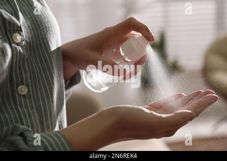 Eine Frau, die in geschlossenen Räumen Antiseptikum auf die Hand spritzt, Nahaufnahme Stockfoto