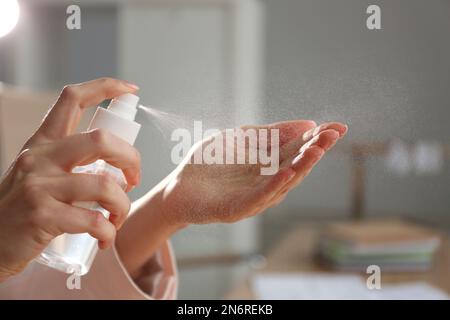 Eine Frau, die in geschlossenen Räumen Antiseptikum auf die Hand spritzt, Nahaufnahme Stockfoto