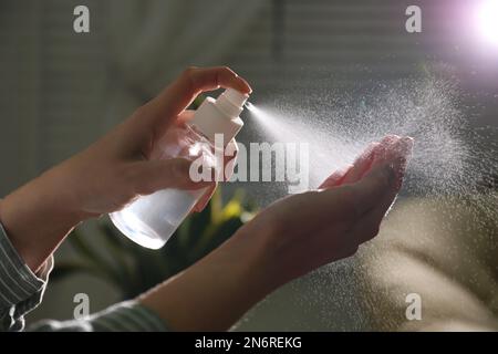 Eine Frau, die in geschlossenen Räumen Antiseptikum auf die Hand spritzt, Nahaufnahme Stockfoto