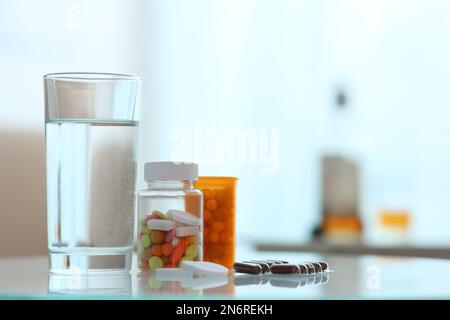 Glas Wasser und Pillen auf dem Tisch drinnen, Platz für Text. Kater-Heilmittel Stockfoto