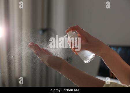 Eine Frau, die in geschlossenen Räumen Antiseptikum auf die Hand spritzt, Nahaufnahme Stockfoto