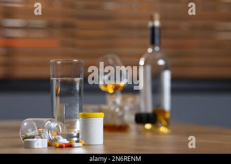 Glas Wasser, Pillen und Alkohol auf dem Tisch drinnen, Platz für Text. Kater-Heilmittel Stockfoto