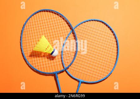 Badminton-Schläger und Shuttle-Hahn auf orangefarbenem Hintergrund, flach liegend. Platz für Text Stockfoto