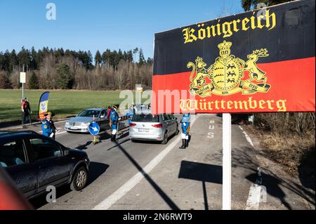 Villingen Schwenningen, Deutschland. 10. Februar 2023. Auf einem Schild in der Nähe einer Mautstraße, wo die Mitglieder des Narrenzunft Gockel-Gilde von Autofahrern, die von Baden nach Württemberg und umgekehrt fahren, eine „Mautgebühr“ verlangen, steht „Königreich Württemberg“. Das eingezogene Geld wird für einen guten Zweck gespendet. In der Vergangenheit trennte eine Staatsgrenze Badeners und Württembergers. Während der Karnevalssaison wird in Villingen-Schwenningen erneut ein Zollhaus errichtet. Es gibt viel Ermutigung - aber manche kehren einfach zurück. Kredit: Silas Stein/dpa/Alamy Live News Stockfoto