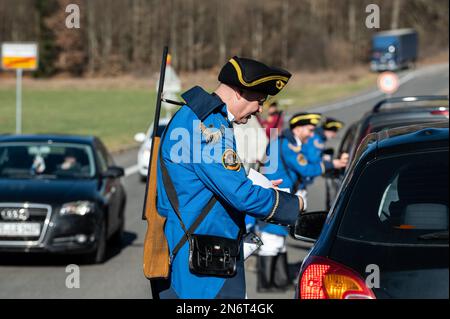 Villingen Schwenningen, Deutschland. 10. Februar 2023. Die Mitglieder des Narrenzunft Gockel-Gilde erheben für Autofahrer, die von Baden nach Württemberg und umgekehrt fahren, eine „Straßenmaut“. Das eingezogene Geld wird für einen guten Zweck gespendet. In der Vergangenheit trennte eine Staatsgrenze Badeners und Württembergers. Während der Karnevalssaison wird in Villingen-Schwenningen erneut ein Zollhaus errichtet. Es gibt viel Ermutigung - aber manche kehren einfach zurück. Kredit: Silas Stein/dpa/Alamy Live News Stockfoto