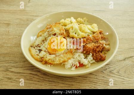 Gebratener Blumenkohl mit knusprigem Hähnchen und reinem Reis mit Eierüberzug auf dem Teller umrühren Stockfoto