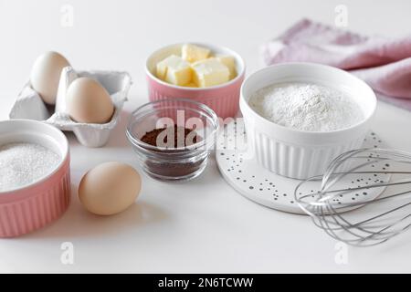 Zutaten zum Backen von Schokoladenkuchen auf einem weißen Tisch Stockfoto