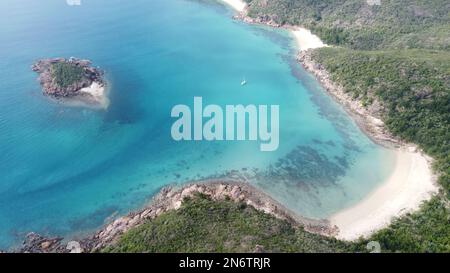 Luftaufnahme eines Bootes, das in einer Bucht vor einer tropischen Insel in den Whitsundays vor Anker liegt Stockfoto