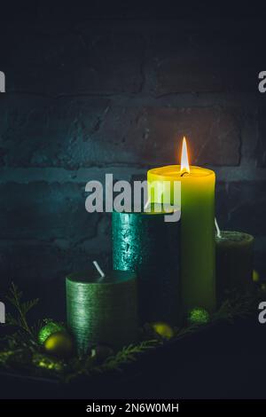 Adventskranz mit vier verschiedenen Kerzen in Grün auf dunklem Hintergrund, weihnachtsdekoration, vertikal mit Kopierbereich Stockfoto