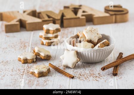 Weihnachtszimtsternkekse auf einem weißen Holztisch, im Hintergrund mit Holzbuchstaben Xmas Stockfoto