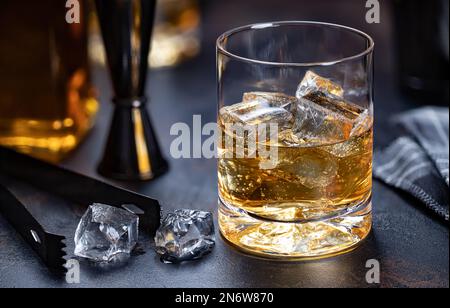 Ein Glas Whiskey mit Eisgetränk auf dunklem Holzhintergrund Stockfoto