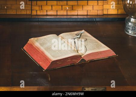 Ein altes Buch mit einer alten Lesebrille auf einem Holztisch Stockfoto