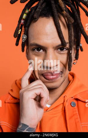 Porträt eines tätowierten und multirassischen Mannes mit Dreadlocks, die auf Korallen lächeln Stockfoto