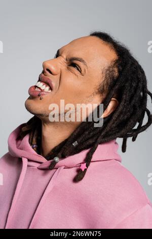 Porträt eines emotional multirassischen Mannes mit Dreadlocks, die aufschauen und grauen Grinsen Stockfoto