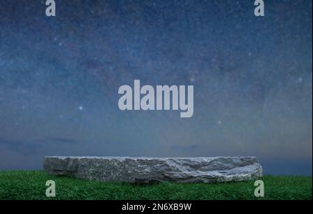 Steingranit-Podium-Tischplatte auf grünem Gras in der Nacht-Skystar-Gegend und Milchstraße-Galaxie Hintergrund.Beauty- oder Kosmetikprodukte-Platzierung Präse Stockfoto