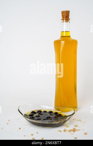 Glasflasche Olivenöl und eingelegte schwarze Oliven, isoliert auf weißem Hintergrund. Stockfoto