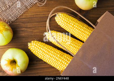 Beutelkost-Konzept. Papiertüte Gemüse und Obst auf dunklem Holzhintergrund mit Kopierbereich, Draufsicht. Lebensmittel Einkaufen Papiertüte mit gesundem Foo Stockfoto