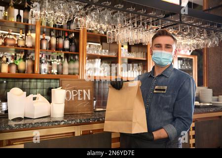 Kellner mit gepackten Speisen zum Mitnehmen im Restaurant. Gastronomie während der Coronavirus-Quarantäne Stockfoto