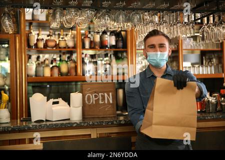 Kellner mit gepackten Speisen zum Mitnehmen im Restaurant. Gastronomie während der Coronavirus-Quarantäne Stockfoto